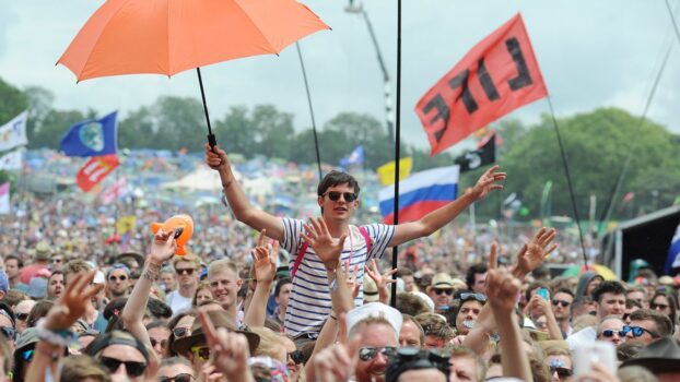 Man in a striped t-shirt, holding an orange umbrella, up on someone